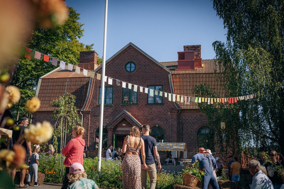 Människor i solen framför skolberget